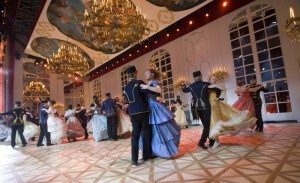 Dancers in the replica of the Viennese ballroom in the Schonbrunn Palace, under the golden chandeliers. If you look hard, you can see the uniformed footmen/doormen. (source: www.andrerieu.com).